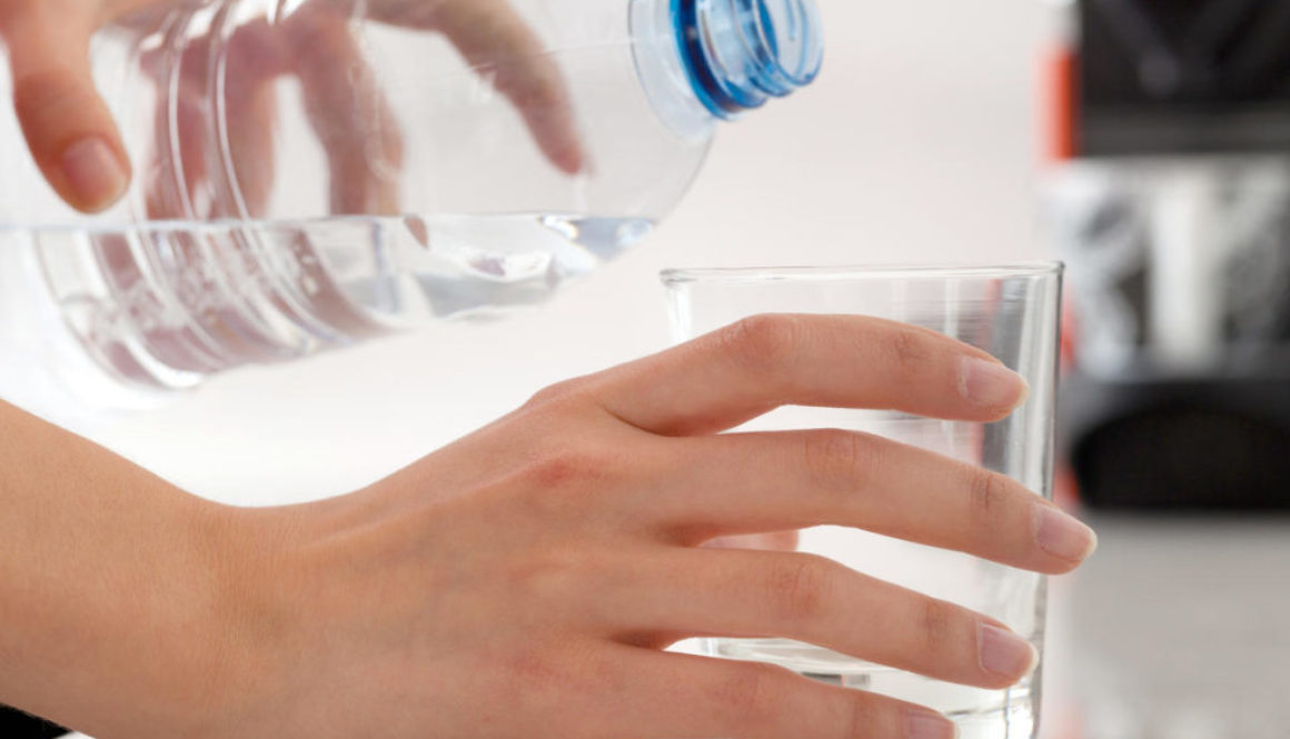 Female hands pouring bottled water into glass